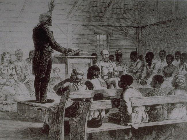 An enslaved person orates to a small congregation in a wooden shack. 