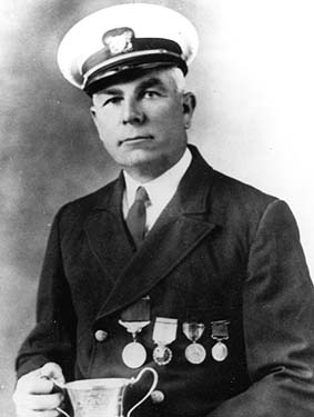 A photograph of John Allen Midgett, Jr. holding a silver cup given to him by the British Board of Trade in honor of his rescue of sailors from the British tanker Mirlo in 1918.